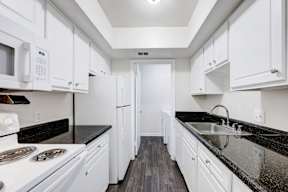 A kitchen with white cabinets and black countertops.