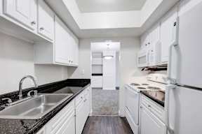 A kitchen with white cabinets and a black countertop.