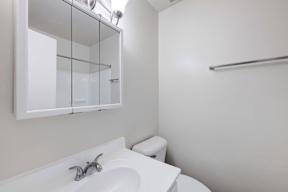 A white bathroom with a sink, toilet, and a mirror.