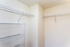 A white closet with three shelves and two hangers.