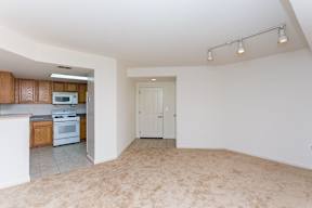 A spacious living room with a kitchen area in the background.