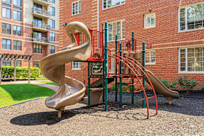 A playground with a red slide and a large brown slide.