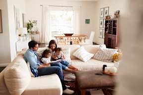 A family of four is sitting on a couch in a living room.
