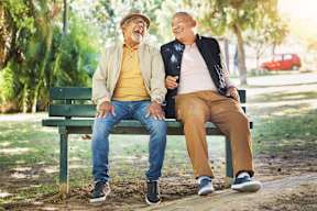 Two men are sitting on a bench in a park.