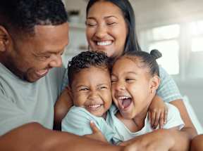 A family of four is hugging and smiling together.