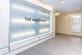 A glass wall with the text "THE MACEDONIAN" on it.