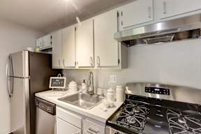 A kitchen with a stove, sink, and refrigerator.