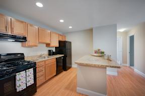 A kitchen with a black stove top oven and wooden cabinets.