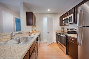 A kitchen with dark cabinets and wood floors
