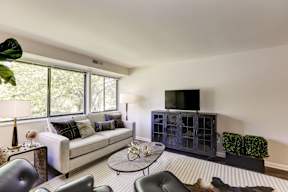 A living room with a white couch and a television on a cabinet.