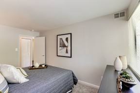 A bedroom with a bed, nightstand, and a painting on the wall.
