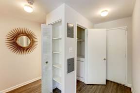 A white closet with a mirror and shelves.