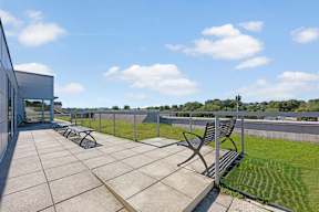 A patio with a bench and a table is surrounded by a fence.