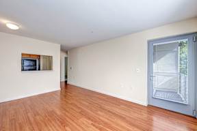 A room with a wooden floor and a television mounted on the wall.
