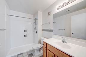 A white bathroom with a toilet, sink, and shower.