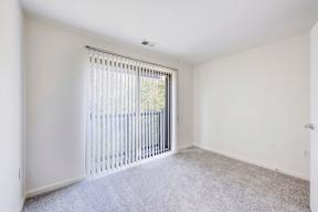 A room with a carpeted floor and a window with blinds.