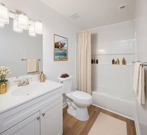 A white toilet sits in a bathroom next to a sink and a bathtub.