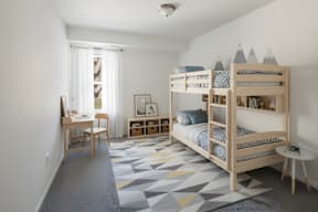 A room with a bunk bed and a desk.