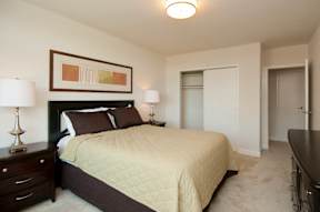 A bedroom with a bed, nightstand, and lamp at Dominion Towers Apartments, Arlington, Virginia