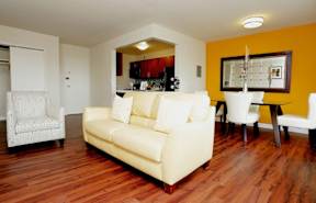 A living room with a yellow couch and a white chair at Dominion Towers Apartments, Arlington, VA, 22204