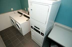 A white dryer and washer in a laundry room at Dominion Towers Apartments, Virginia, 22204