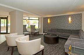 A living room with a grey couch and white armchairs at Dominion Towers Apartments, Arlington, VA, 22204