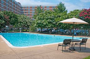 A pool with chairs and an umbrella in front of a building at Dominion Towers Apartments, Virginia