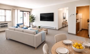 A modern living room with a large couch and a television mounted on the wall.