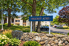 A sign that says Hillcrest Acres stands in front of a building.