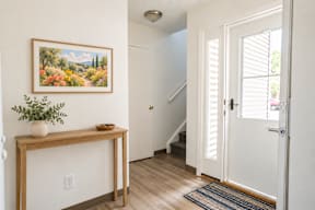 A painting of a landscape hangs on a wall above a wooden table.