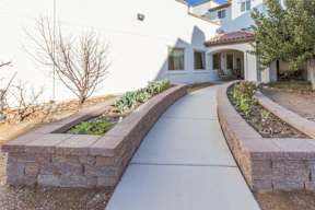 A white house with a grey walkway in front.