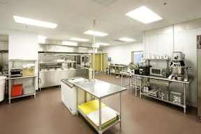 A clean, well-organized commercial kitchen with stainless steel appliances and workstations.