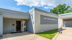 The Bald Eagle Reception Center is a modern building with a white exterior and a glass door at Eagles Crossing Apartments, Washington