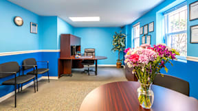A conference room with a table, chairs, and a vase of flowers at Eagles Crossing Apartments, Washington DC