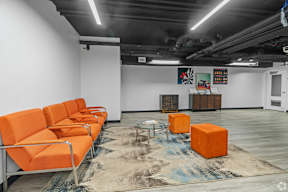 Orange chairs are arranged in a row in a room with a rug on the floor.