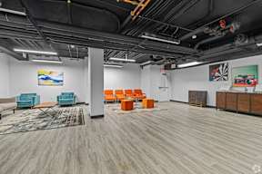 A room with a wooden floor and a white wall with a painting on it.