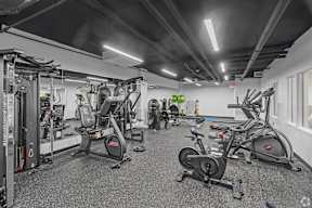 A gym with a variety of exercise equipment including treadmills, stationary bikes, and weight machines.
