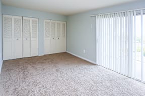 A room with a carpeted floor and three white closets.