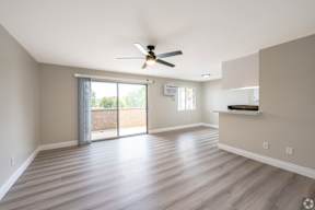 A room with a ceiling fan and sliding glass doors.