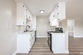 A white kitchen with a black stove top oven.