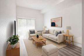 A living room with a white couch, a wooden coffee table, and a potted plant.