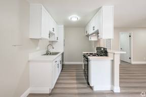 A kitchen with white cabinets and a white island.