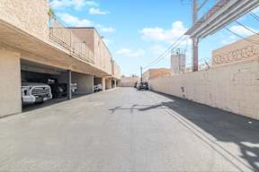 A street with cars parked on the side and buildings on both sides.