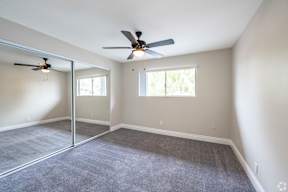 A room with a ceiling fan and sliding glass doors.