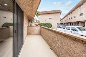 A balcony with a concrete wall and a glass door.