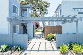 A white house with a wooden pergola in front.