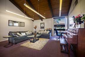 A living room with a couch, a coffee table, and a piano.