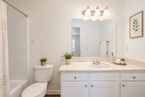 A white bathroom with a toilet, sink, and mirror.