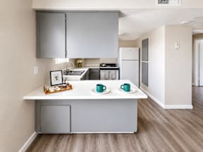 A kitchen with a white countertop and grey cabinets.