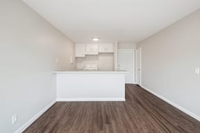 A kitchen with white cabinets and a wooden floor.